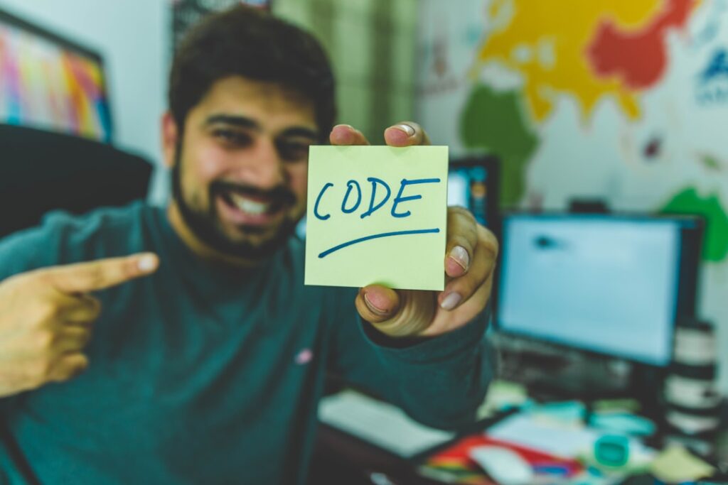 Um rapaz apontando para um post-it escrito Code